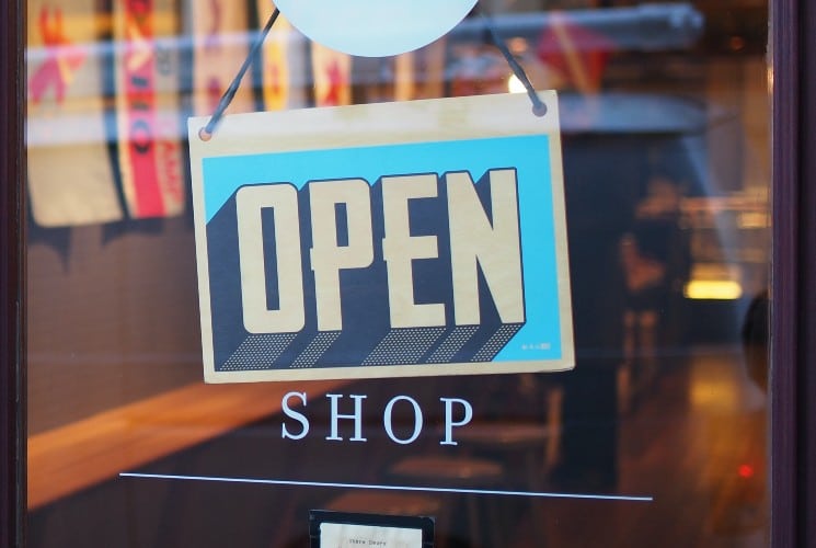 Window of a store with a blue and white OPEN sign