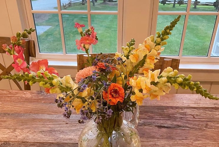 A gorgeous bouquet of orange, yellow and purple flowers on a table in front of a window