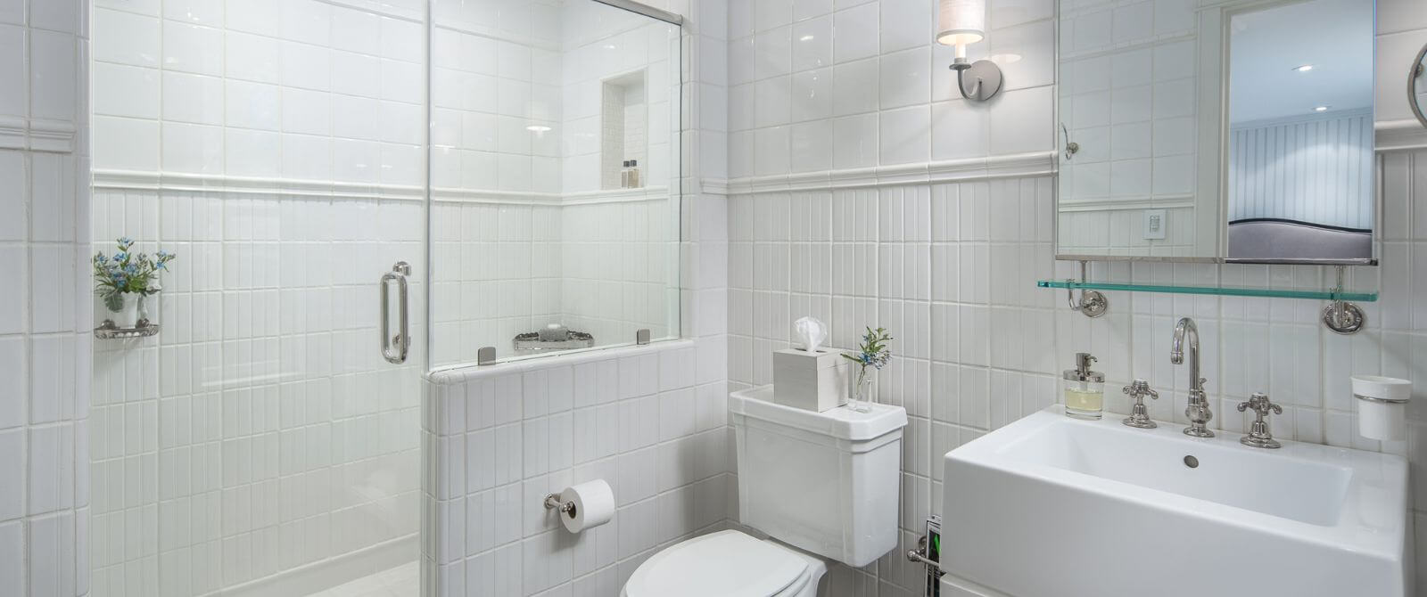 Elegant white bathroom with square sink, mirror, toilet and walk in shower with glass doors
