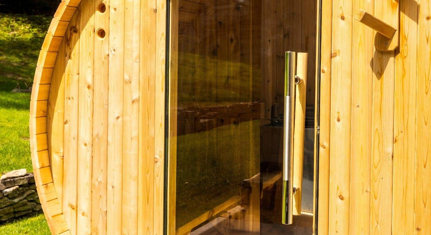 Large round wooden outdoor sauna with a glass door